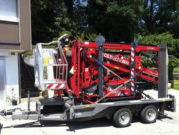 Nacelle élévatrice araignée rouge chargée sur sa remorque de transport